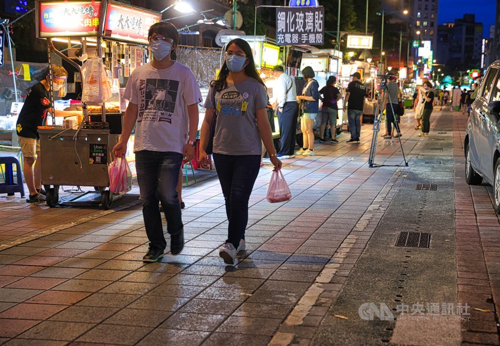台北寧夏夜市29日晚間「微解封」,採「單邊攤商營業、得來速外帶型態」,僅提供外帶,商家、客人皆需落實戴口罩等各項防疫措施。復業首日即有不少民眾前往,購買睽違許久的夜市小吃。中央社記者謝佳璋攝 110年6月29日